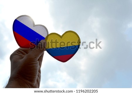 Hand holds a heart Shape Russia and Colombia flag, love between two countries