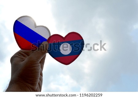 Hand holds a heart Shape Russia and Laos flag, love between two countries