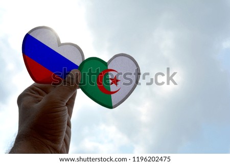 Hand holds a heart Shape Russia and Algeria flag, love between two countries