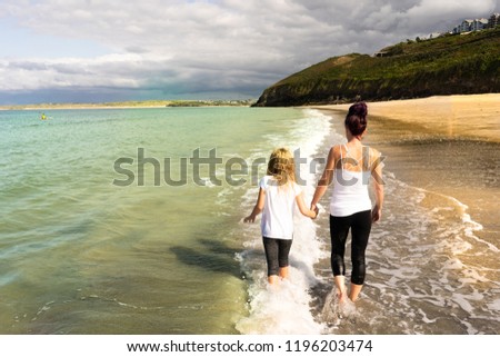 Mother and Daughter happy, smiling, paddling, walking in the sea at the gorgeous St Ives in Cornwall, UK, the stunning Carbis Bay