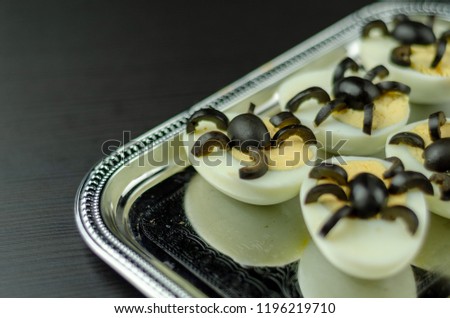 funny snack with olive spiders on egg halves for halloween party, creative food application, scary