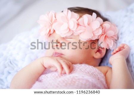 Sweet newborn Caucasian baby sleeping. Pink flower head band. New born child photo session.