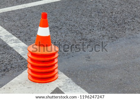 Road cones collected in a stack on asphalt with a marking. Copy space on the right.