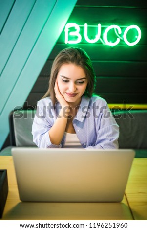 Young woman keyboarding on laptop computer while sitting in cafe. Woman working on net-book after her lectures in University.
