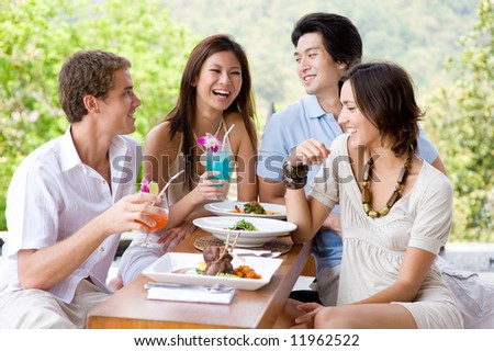 Four young adults enjoying a meal together on vacation Royalty-Free Stock Photo #11962522