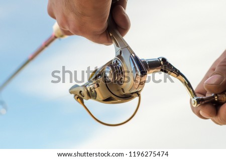 Fisherman's hand with a fishing rod on a blue background close-up