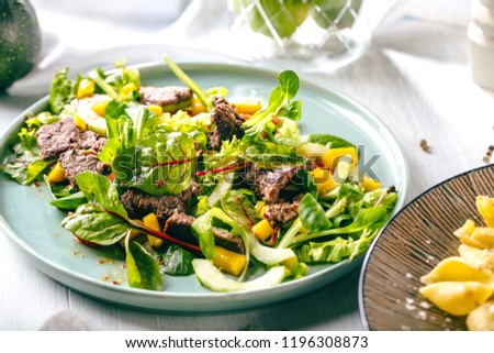Fresh salad plate with mixed greens (arugula, mesclun, mache) on dark wooden background close up. MANZO