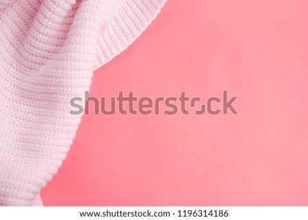 Pink knitted clothes on a pink paper background. Bedding with a pink knitted plaid. Copy space. Flat lay, top view
