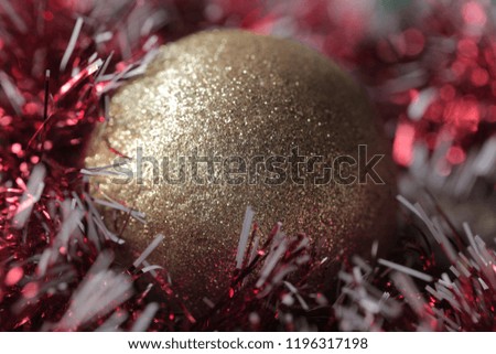 Christmas ornament close up - golden glitter sparkling ball with a red and silver tinsel going around, with bright reflection, macro photography