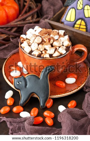 Homemade gingerbread cookies in the form of black cаts and hot chocolate mug for  Halloween holiday, selective focus  with shallow depth of field