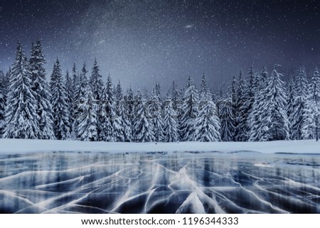 Dairy Star Trek above the winter woods. Cracks on the surface of the blue ice near hills of pines. Frozen lake in mountains. Carpathian Ukraine Europe.
