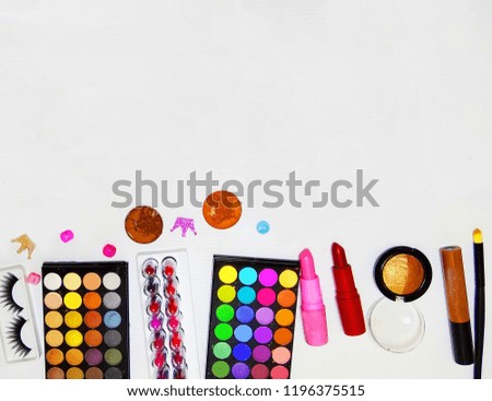Many cosmetic Lined on a white background, such as powder, lipstick, nail polish, highlights false eyelashes, makeup brushes, eye shadow and blush.