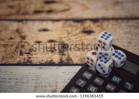 Conceptual image calculator with dice on wooden background. Concept for business risk, chance, good luck or gambling. Copy space for text. Selective focus.

