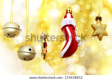 Christmas bells, glove and stars hanging over golden bokeh background