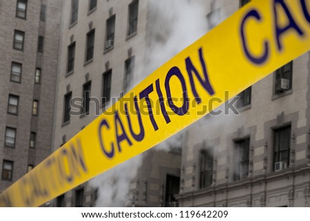 Caution yellow tape in front of building with smoke