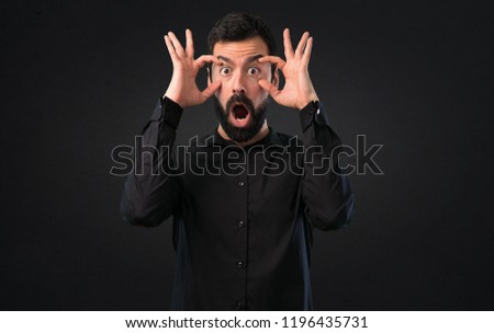 Handsome man with beard showing something on black background