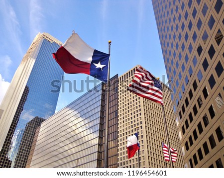Low angle view of United States of America flag and Texas state flag in front of modern skyscrapers in downtown Houston (skyline / skyscrapers) on a summer day - Houston, Texas, USA 