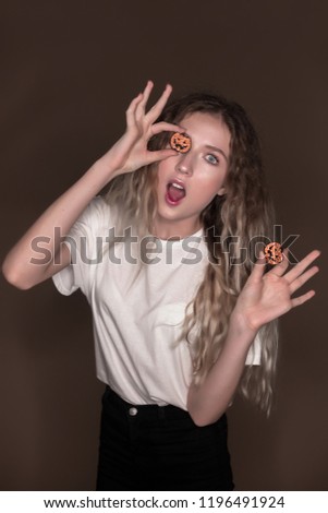 Portrait of beautiful young shocked surprised excited woman posing isolated over dark beige background wall holding pumpkin halloween glitter decor in hands.