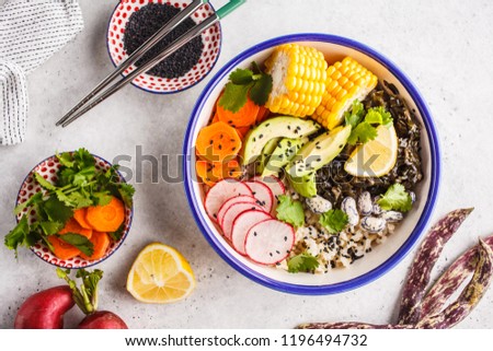 Flat lay vegan poke bowl with brown rice, sea kale and vegetables on white background.
