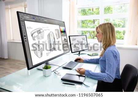 Side View Of A Young Female Designer Using Graphic Tablet While Working On Computer