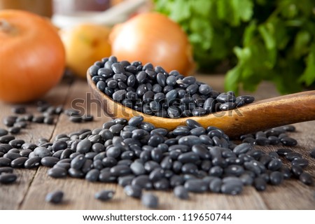 Black beans in a wooden spoon with cilantro and onions in the background Royalty-Free Stock Photo #119650744