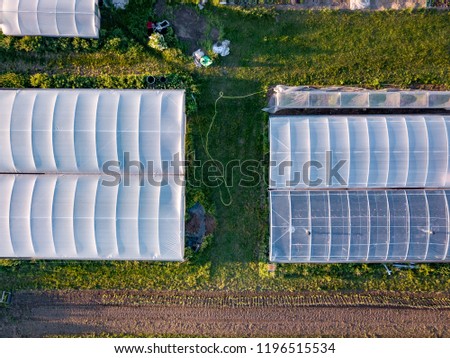 Drone aerial photography of an organic inner city farm taken at sun set in London. Polytunnels, agricultural buildings and farmland taken on the outskirts of a city.