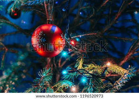 Festive background with christmas ball and garland hanging from fir branches