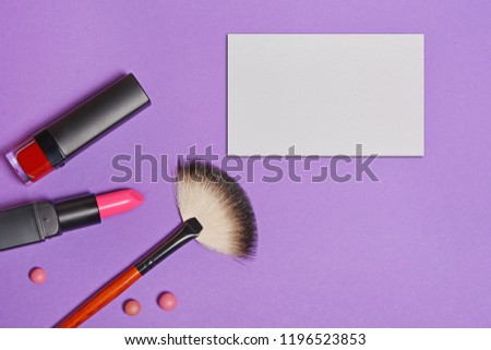 Top view on set of beauty products: decorative cosmetics as lip stick, nail polish, makeup brush and mock-up business card on bright purple background
