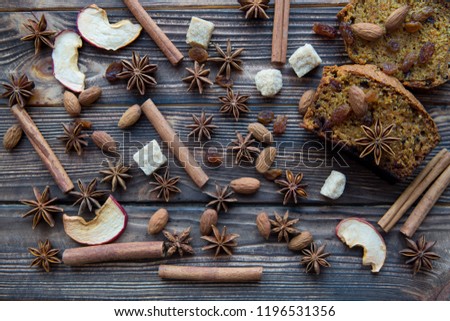 Homemade spicy pumpkin cake slices with walnuts, brown sugar, anise stars, raisins, dried apples, cloves, cinnamon on rustic wooden brown background. Christmas mood tasty dessert, top view. 