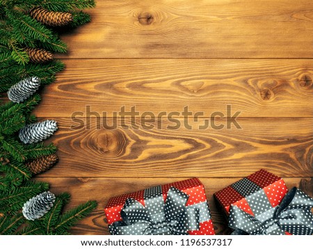 Christmas composition. Fir branches with cones along with gift boxes on the wooden background. Top view. Holiday concept