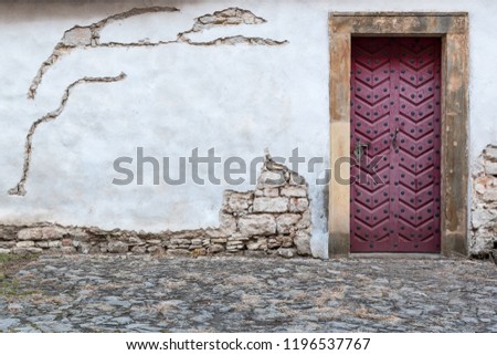 Fortress wall of a church Saint Wencesllas, Stara Boleslav, Czech Republic, close-up look at the decorated color wooden door surrounded by white old wall.