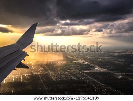 photo taken through airplane window of Storm clouds and rain reflecting light looking down on city.  Travel Concept