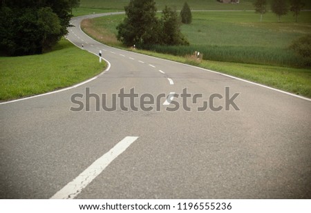 A winding asphalt road. Cross lines on road, Close up view of a road in curves. A asphalt road through a european village