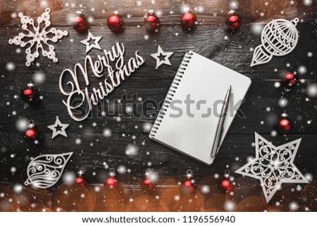 Christmas background with blank notebook, baubles, wooden decorations and snow effect. Space for text, top view