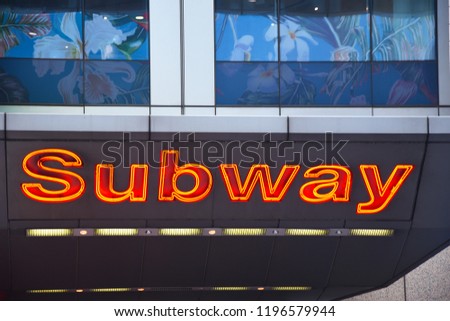 Lit up neon subway entrance sign in New York City