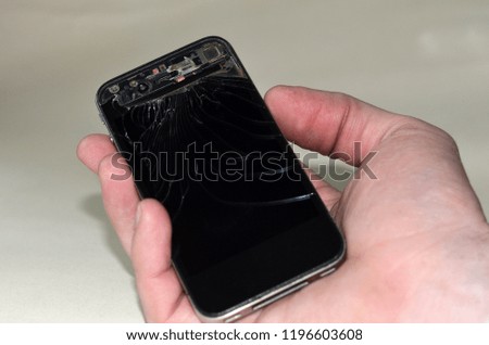 Broken mobile gadget in hand on a white background. Cracked glass mrbtlnogo smartphone