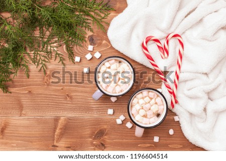 Christmas and New Year flat lay.Top view on a Christmas tree, a warm plaid, cups with cocoa and marshmallows and Christmas candy canes on a wooden background with space for text