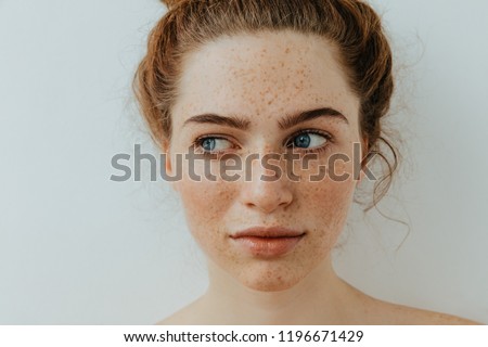 Calm and pretty. Close-up. Beautiful blue eyed girl with freckles is looking away, on a white background Royalty-Free Stock Photo #1196671429