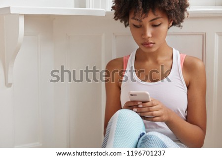 Cropped image of concentrated blogger with Afro hairstyle makes internet publication on website, messages in chat, wears casual clothes, connected to wireless internet at home. Technology concept