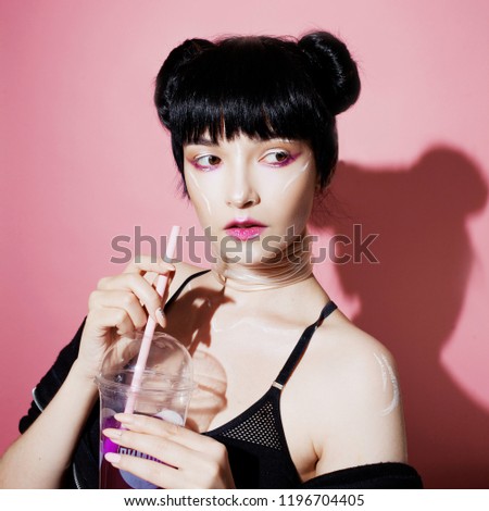Cyber girl. Beautiful young woman, futuristic style. Portrait of a trendy girl drinking soda on a pink background