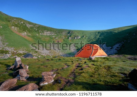 Tourism and traveling concept. Beautiful summer landscape with mountains and tourist tent.