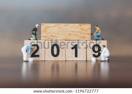 Miniature worker team painting  on wooden block , Happy new year 2019 concept