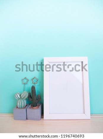 Mock up white frame and cactus on wooden table, white frame for design presentation, copy space.