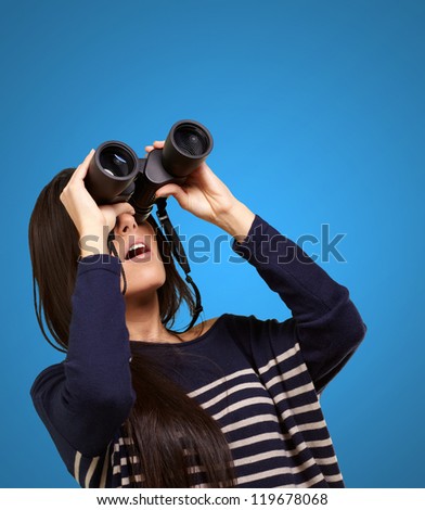 portrait of young girl looking through a binoculars over blue