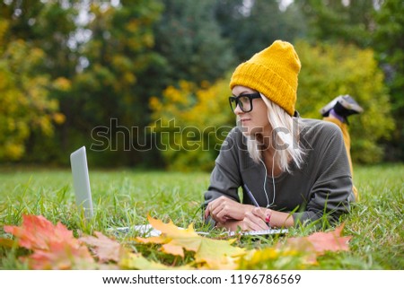 A young freelancer girl working with a laptop on the Internet, relaxing in the park. Communication, education and distance work.