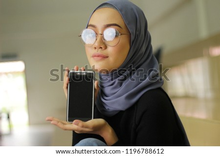 Beautiful Asian women with smile holding a new phone technology. Blue hijab style and fashion
