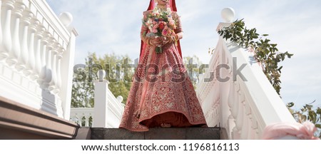 Pakistani  Indian bride showing in a red lengha wedding and holding bouquet Royalty-Free Stock Photo #1196816113