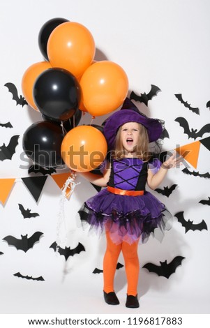 Young girl in halloween costume with balloons on white background