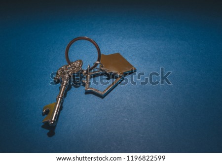 Key and house shape keychain on blue background.Property investment concept.