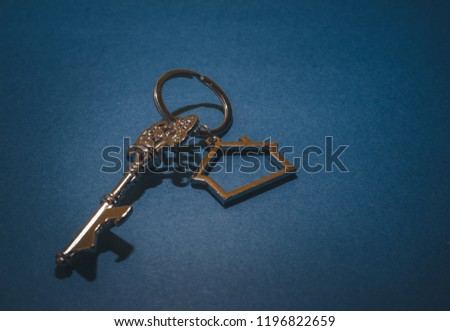 Key and house shape keychain on blue background.Property investment concept.